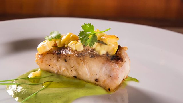 sea bass with green sauce and cashew fruit. Front view with smoke.