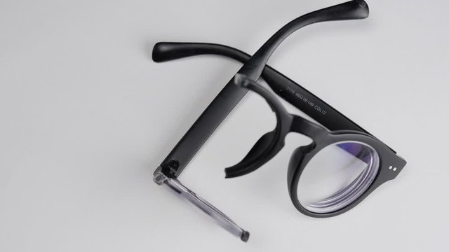 Rotating broken black glasses with diopters on a white background.Close-up.