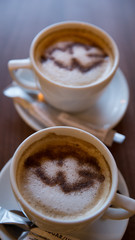 Two cappuccino mugs on which a heart is drawn.