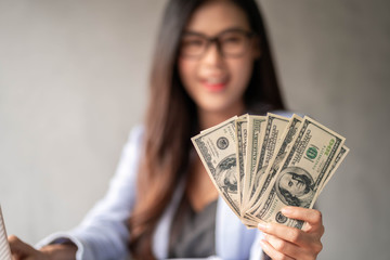 Dollar in a businesswoman hand. An Asia woman is working from home or office and glad to get dollar money from work and from a supplementary career or Part-time self-employment.