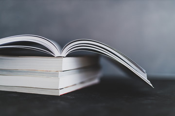 stack of books with one open on top of them shot from eye level with shallow depth of field.