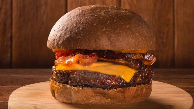 Tasty and appetizing hamburger cheeseburger pork with bacon. Front view with smoke.