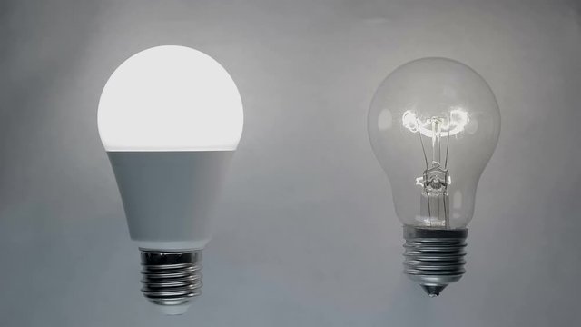 Energy-saving, eco-friendly Led bulb lamp compared to a classic glass tungsten filament lamp are lights up on a light background. Closeup