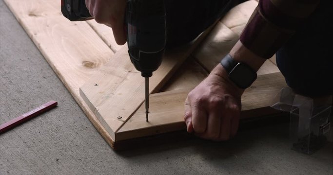 Man driving in screw with cordless drill - close up