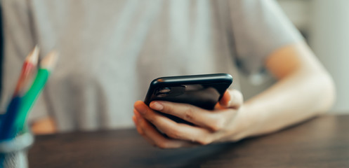 Closeup of young woman hand holding smartphone and chatting with friends at social network.