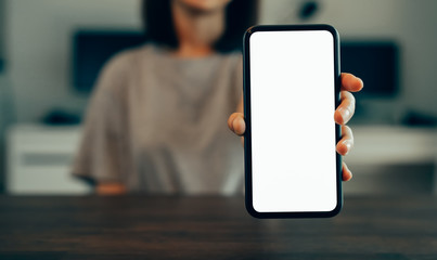 Closeup of young woman hand holding smartphone on the table and the screen is blank, social network concept..