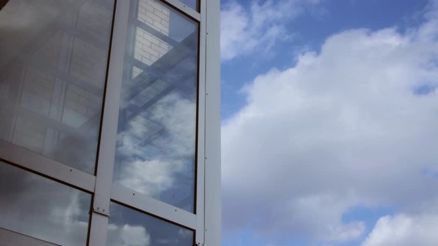 Timelapse of clouds on blue sky and as reflection on glass