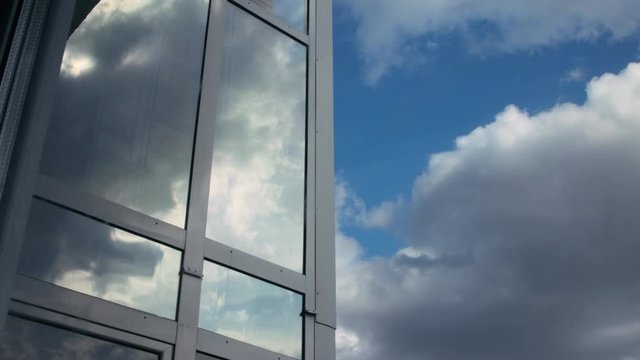Timelapse of clouds on blue sky and as reflection on glass