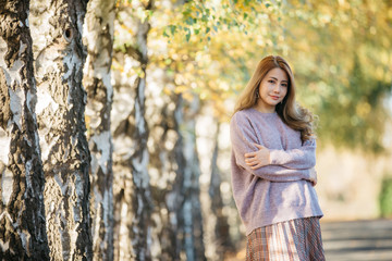 Beautiful asian woman with autumn leaves, flower and fall yellow leaves background at  Christchruch, New Zealand.