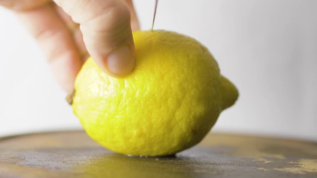 Knife cuts juicy lemon on wood table. Juice flows onto the cutting board. Close Up of fruit, in Slow Motion Lemmon.