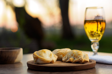 Argentine empanadas on a wood plate and beer outside