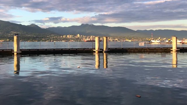 Lake series scene Golden hour dock on Vancouver inlet, distant clouds and mountains, water reflects sky