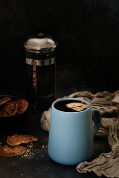 Black coffee in a mug, chocolate cookies and coffee plunger.