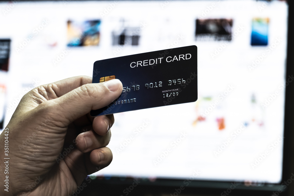 Poster credit card in hand with online shopping website monitor background. concept for technology and e-co