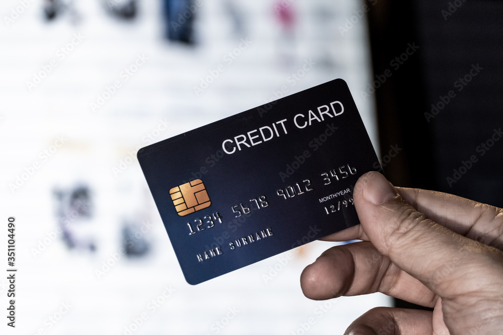 Poster credit card in hand with online shopping website monitor background. concept for technology and e-co