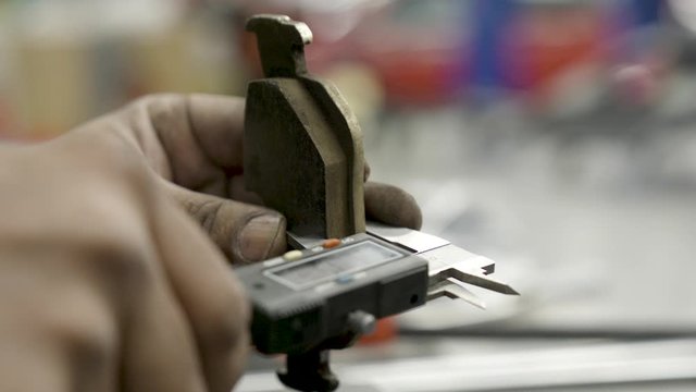 Auto mechanic checks the brake pads of a car during automotive servicing check. The professional technician inspects the auto part and measures the distance of pad that remains with a caliper tool.