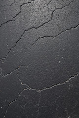 Obraz premium cracked black asphalt surface, texture, pattern, background. Vertical photo. Flat lay.