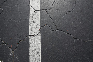 Obraz premium cracked black asphalt with white dividing strip on the pavement texture, pattern, background. Flat lay. Top view.