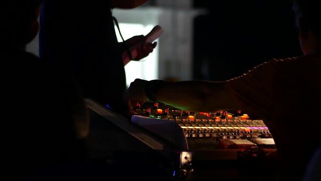 Sound engineer working to prepare for music concert stage. Controlling sound levels for recording speech and music.