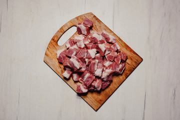 red meat with lard cut into pieces on a cutting wooden board top view