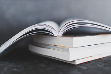 stack of books with one open on top of themshot from eye level with shallow depth of field