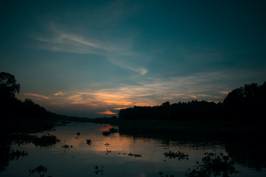 silhouette sunset landscape over a kalindri river of malda with orange and blue sky
