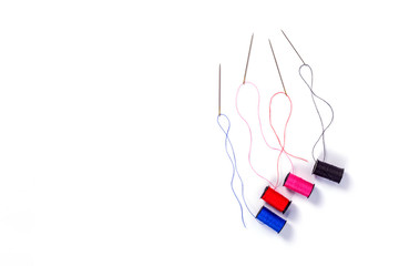 Needle and Color sewing threads on white background, top view
