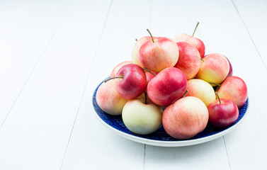 Ripe apples on a plate on a light background, close-up. The harvest of autumn apples. Copy space.