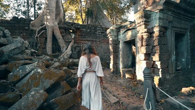 A young woman walking in the iconic movie set used in Tomb Raiders, Ta Prohm Temple, Cambodia, slow motion