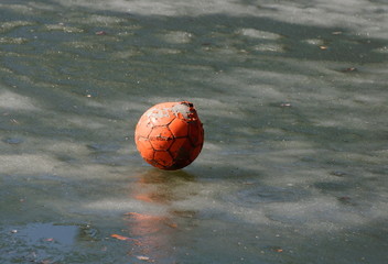 An old ragged ball is lying on the ice of a pond on a spring morning. Moscow region. Russia.