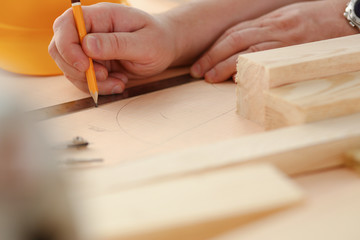 Arms of worker measuring wooden bar