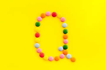 Letter Q - alphabet made with sweets on yellow from above