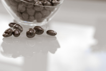 raisins in chocolate in a glass bowl on a glossy light surface
