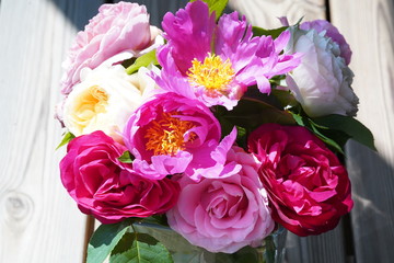 bouquet of red, pink and white roses and peonies on wooden floor, from above