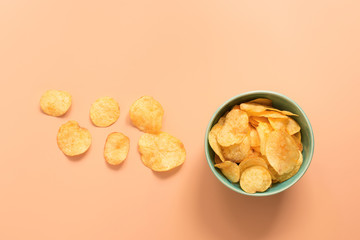 Potato chips in a bowl on a pastel pink background. Top view, copy space.