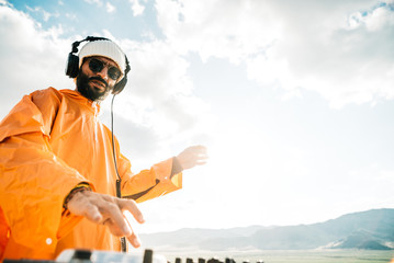 bearded dj playing music outside in the sunset