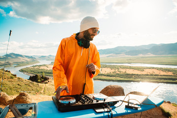 bearded dj in colorful clothes plays music outdoor
