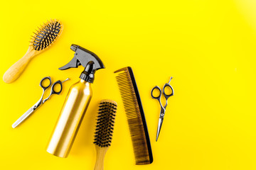 Hairdresser set in beauty salon. Combs, scissors, spray on yellow desk top-down