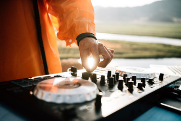 shot of dj's hands playing  music in the sunset