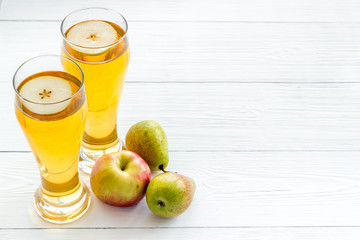 Glasses of beer with apple and peer on white wooden table copy space