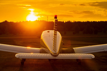 Rear view of a parked small plane on a sunset background. Silhouette of a private airplane landed...