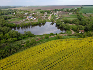 Fototapeta na wymiar Local historian over a rapeseed field and a view of a lake, a river and a small village.