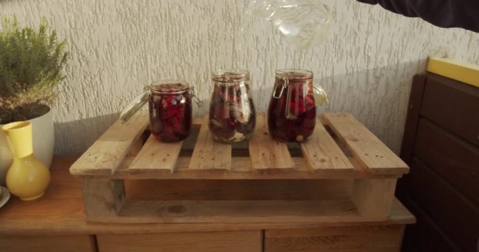 Hand pouring water into glass jar full of chopped beets to pickle them. Slow Motion