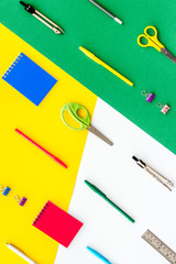 School supplies pattern - notebook, pen, ruler, sciccors - on colorful table top-down