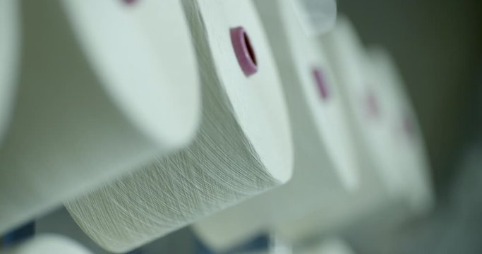 Cotton yarn processing, cotton fibre wound and spun on to cones or cotton reels which await use in further textile production and manufacture.