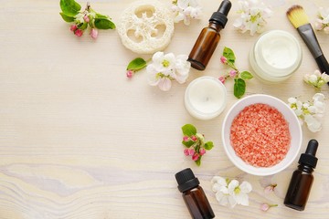 Face and body skin care products, beauty, spa composition with bath salt, essential oils, creme, cosmetic brush, flat lay with spring flowers.