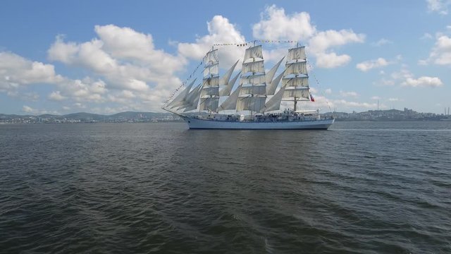 Aerial approaching Unique huge historic ship sails. Boat against backdrop Vladivostok. Sun squatter huge sails. travel cruise regatta. Navigation. Scenic landscape, blue sky with clouds, sunny. Russia