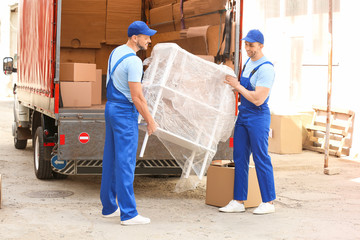 Fototapeta premium Loaders taking furniture from truck outdoors