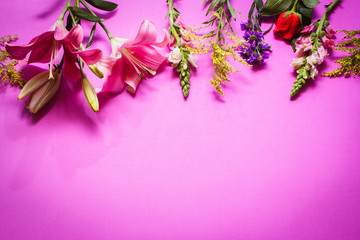 Flores de diferentes colores en fondo rosa 