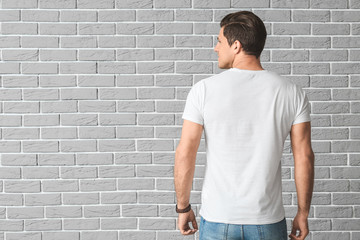 Man in stylish t-shirt on brick background